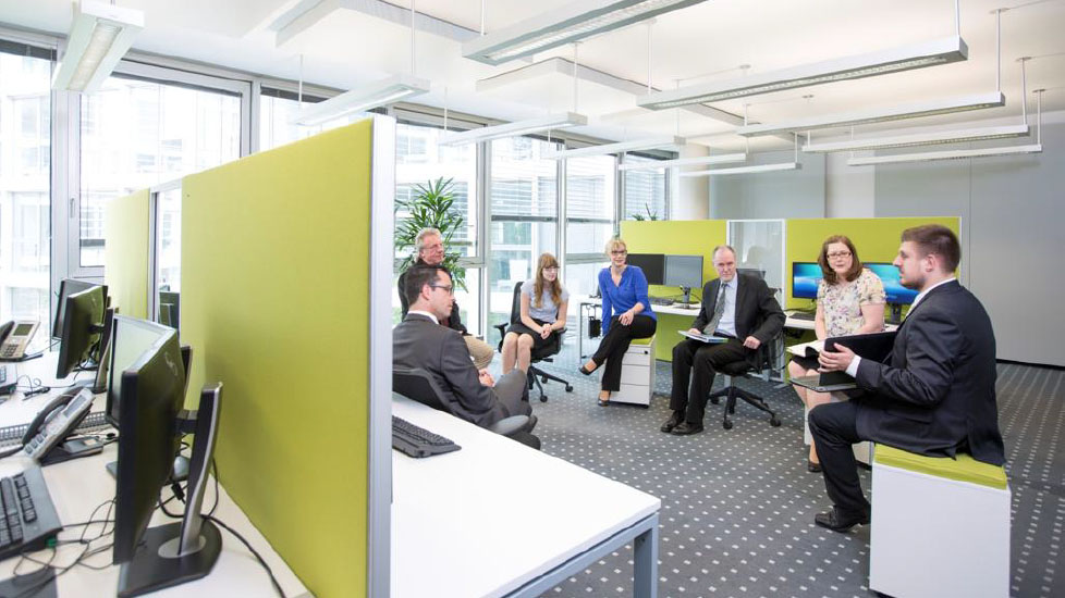 Offene Bürolandschaft der RheinLand Versicherungen in Neuss mit Teamarbeitsplätzen, Akustiktrennwänden und Besprechungszone.