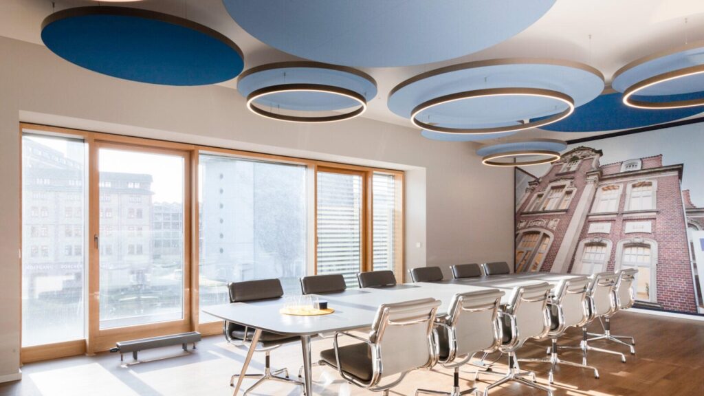 Ein Konferenzraum mit blauen Wänden und Holzböden, eingerichtet mit Akustik Vitra USM Haller Möbeln.
