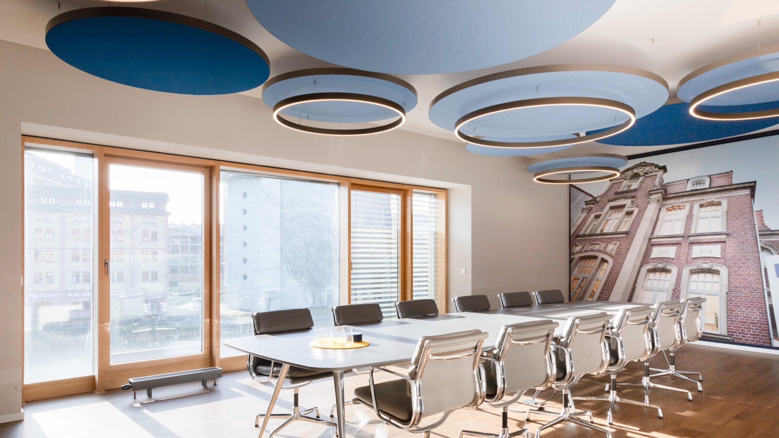 Ein Konferenzraum mit blauen Wänden und Holzböden, eingerichtet mit Akustik Vitra USM Haller Möbeln.