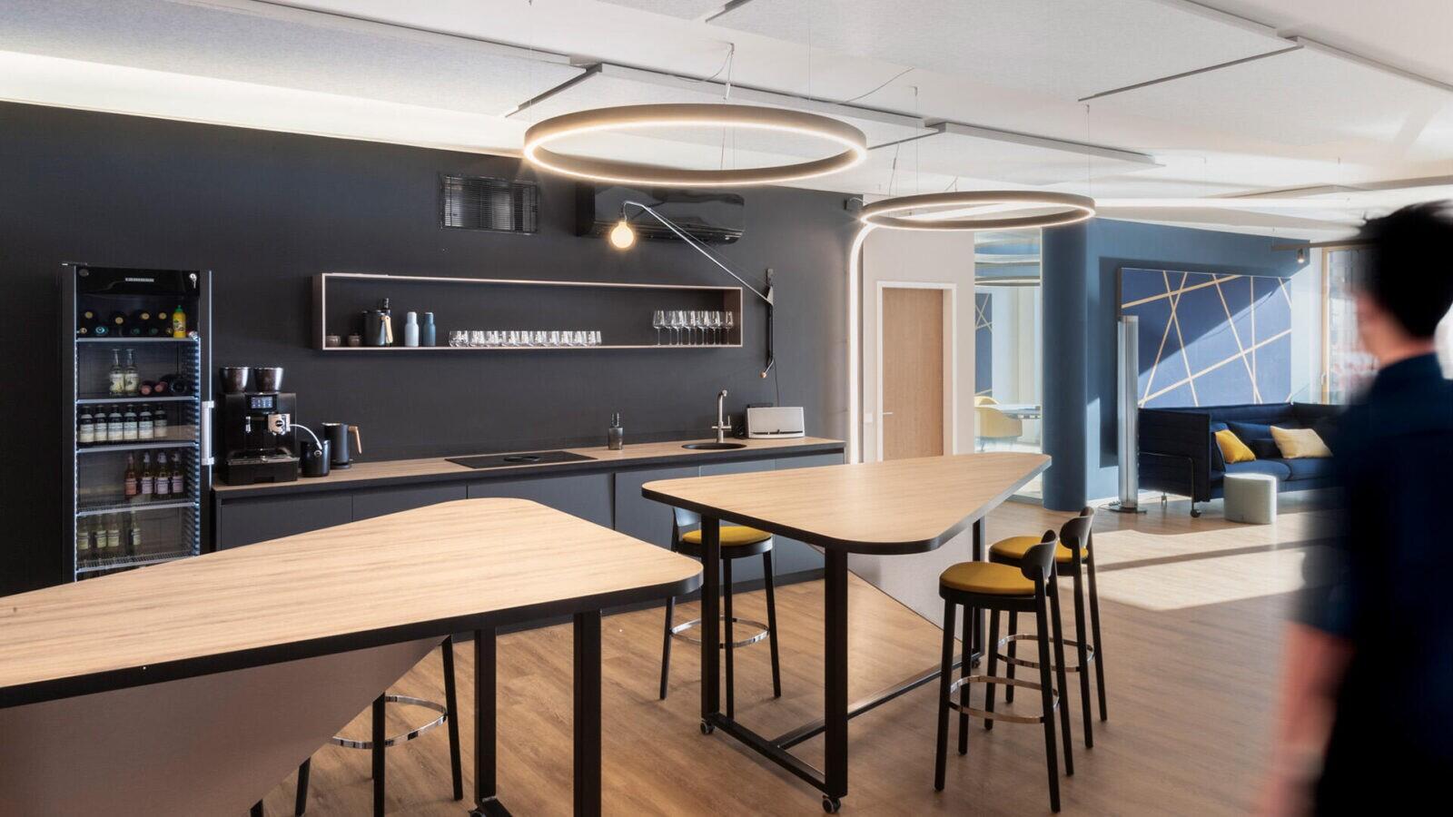 Ein Mann geht durch ein modernes Büro mit Innenausbau Küche.